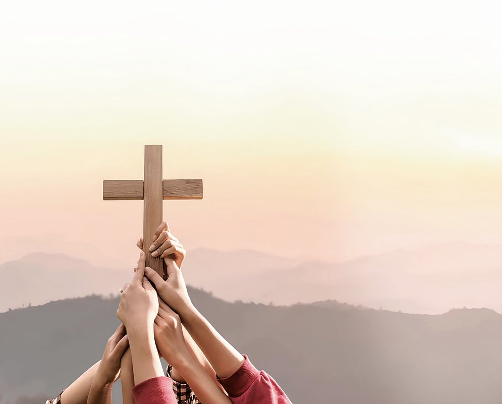 Several hands holding up a cross